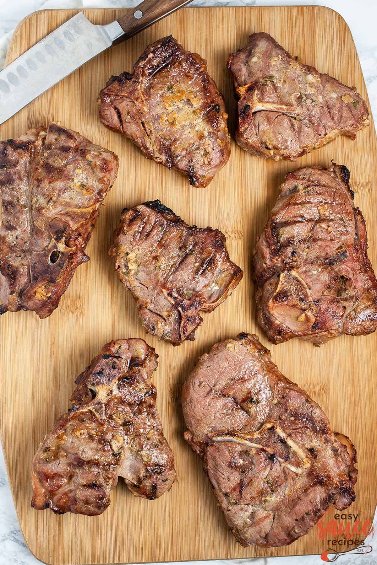 cooked lamb chops on a cutting board with a knife