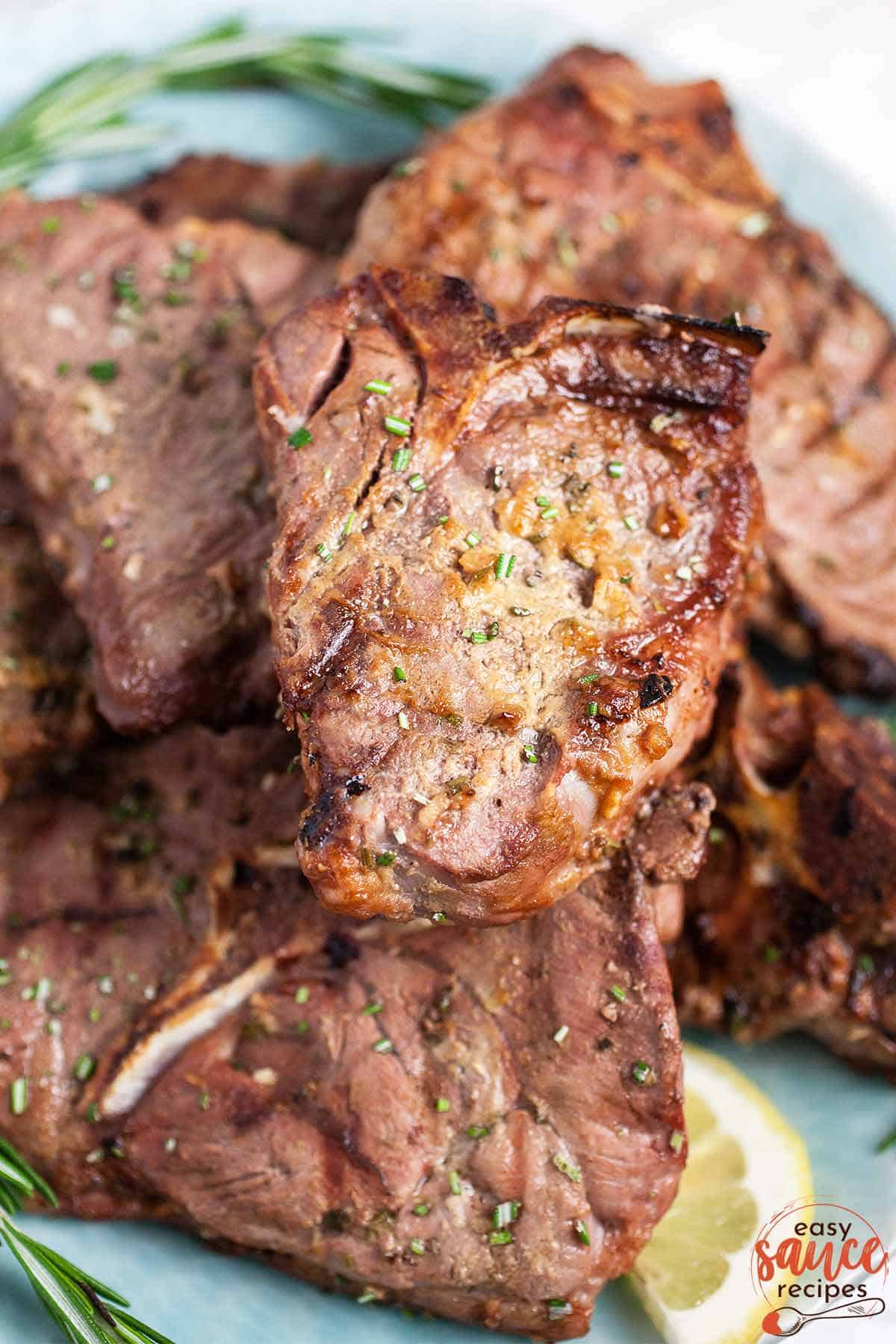 grilled lamb chops stacked on top of each other on a blue platter