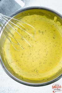 bearnaise sauce being whisked in a metal bowl