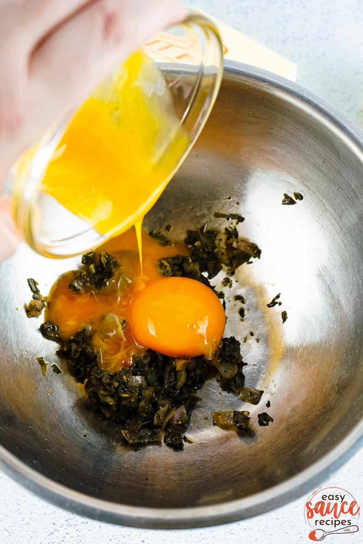 adding egg yolks to the reduced vinegar and herbs in a metal bowl