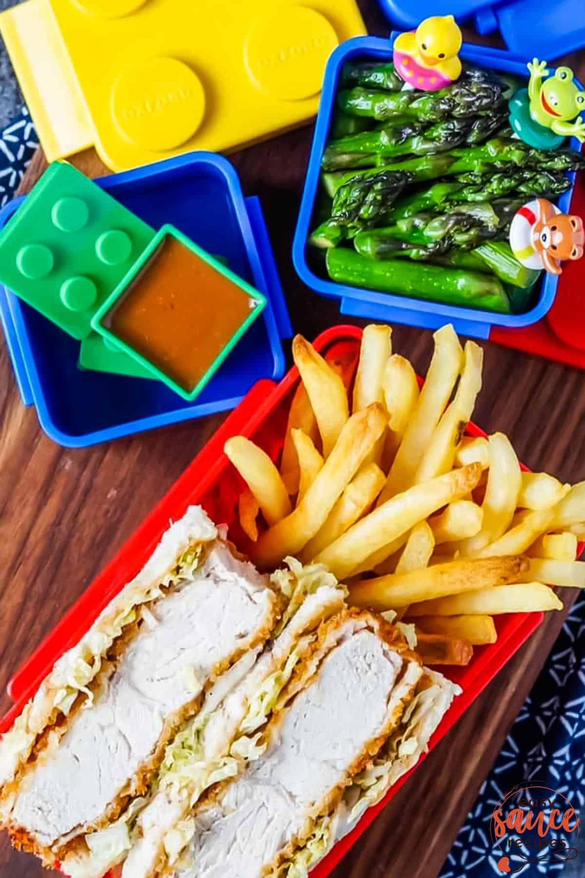 colorful building block food containers with asparagus, pork cutlet sandwiches, french fries and katsu sauce inside.
