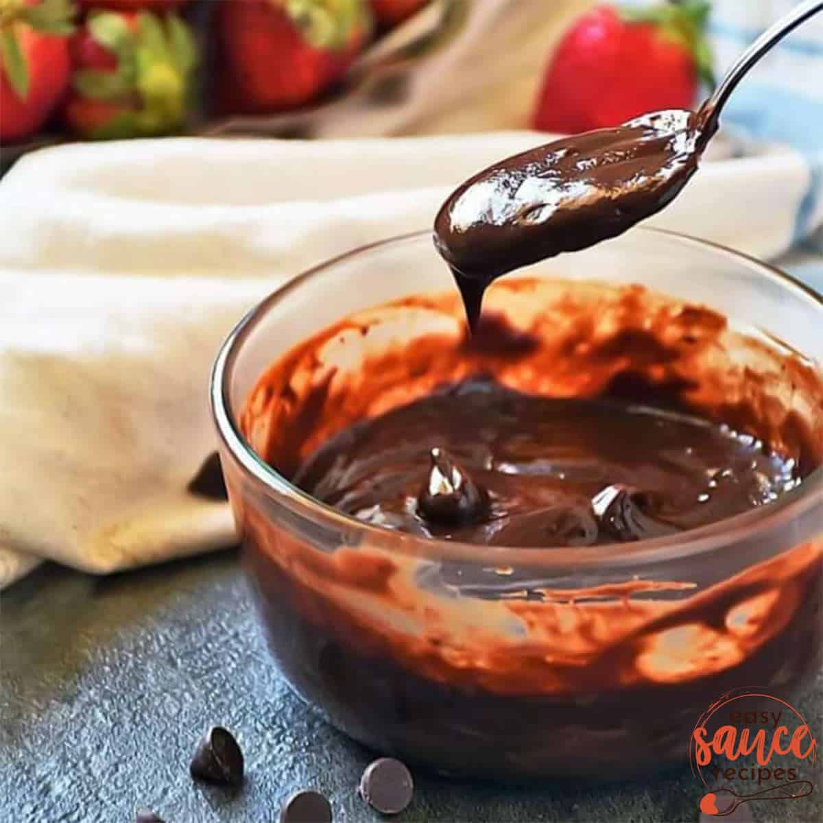 a bowl of chocolate ganache and a spoon drizzling some ganache