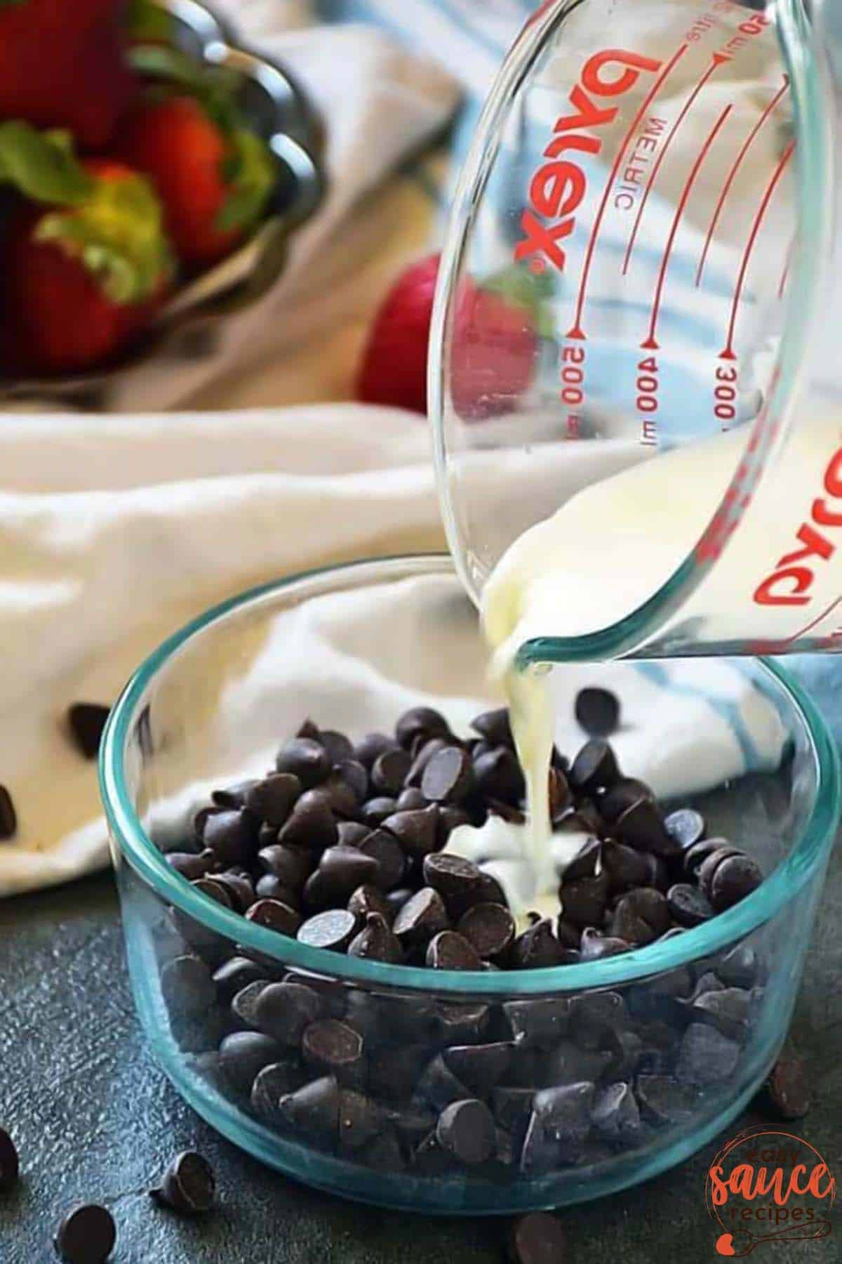 pouring hot cream over chocolate chips in a bowl