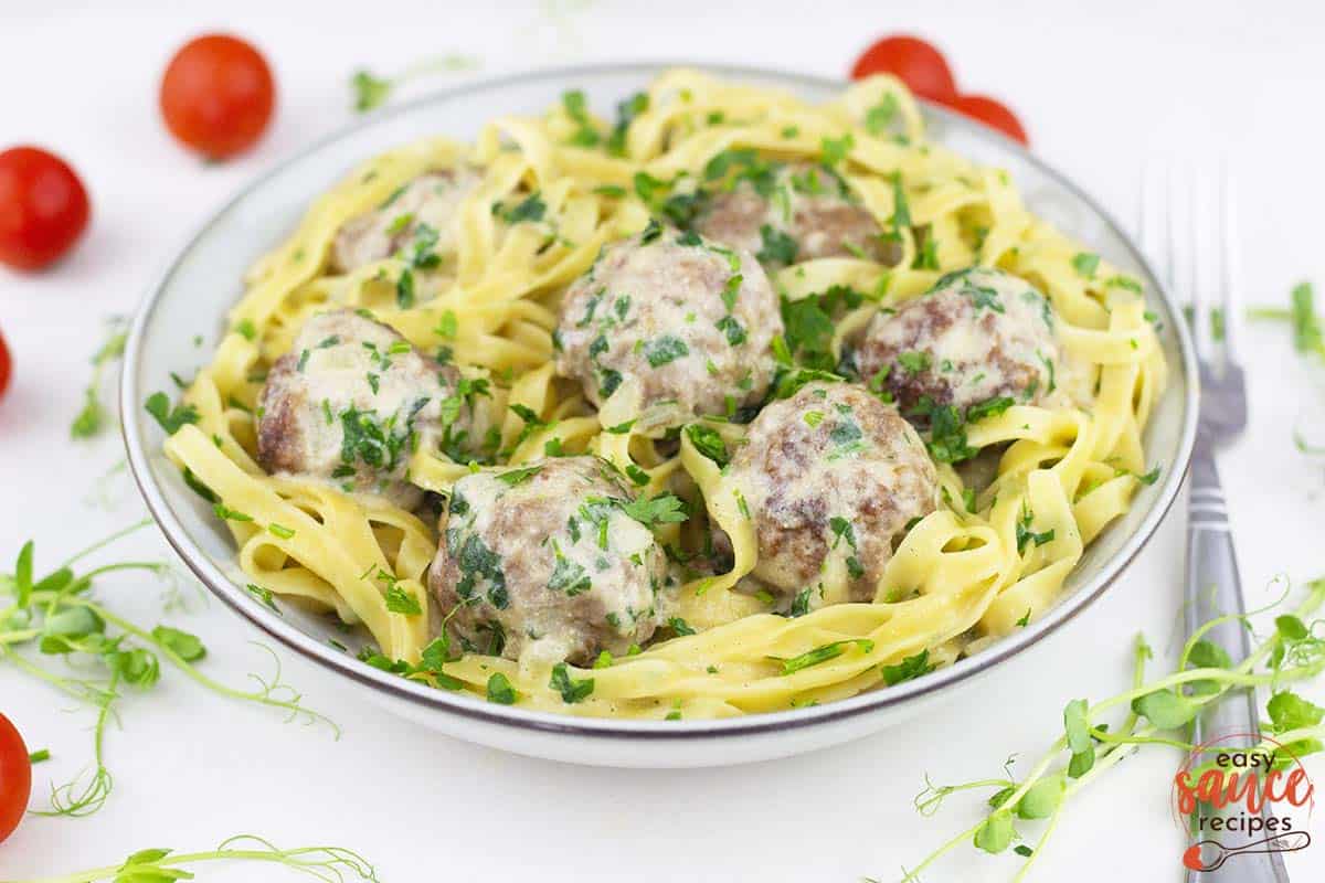 swedish meatballs in a dish with egg noodles and parsley