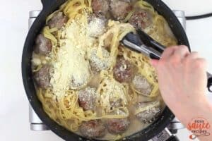 mixing parmesan into the swedish meatballs sauce and pasta