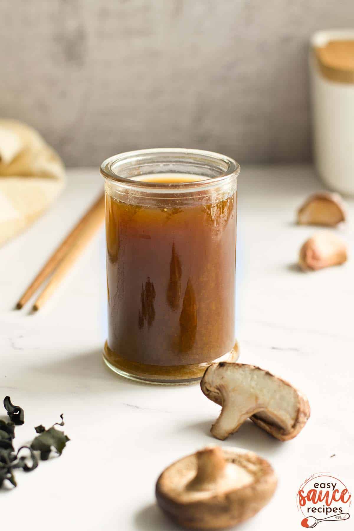 vegan fish sauce in a glass next to mushrooms seaweed and garlic