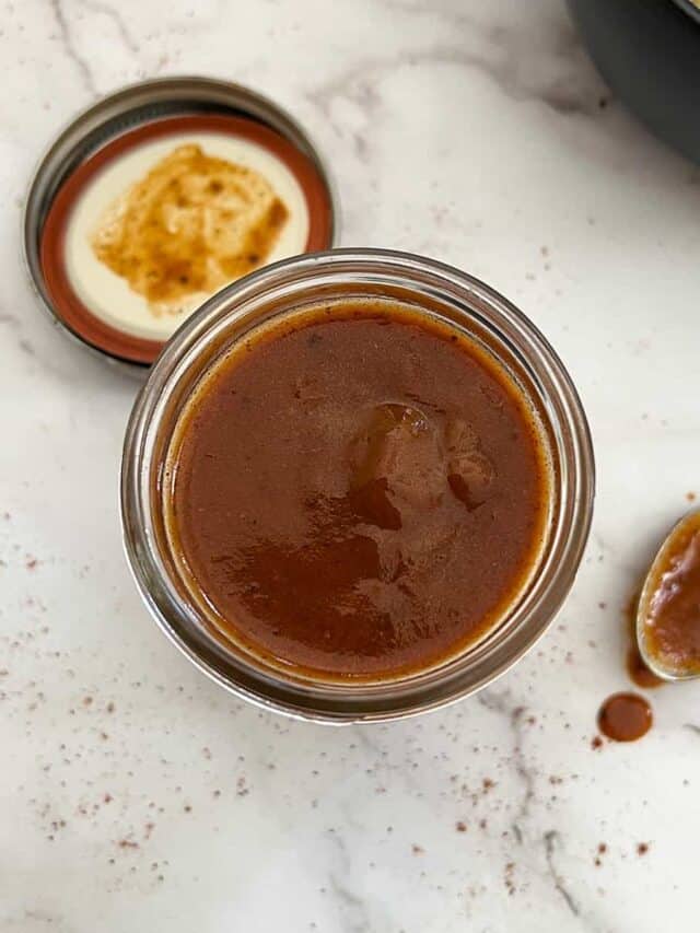 enchilada sauce in a clear jar with a spoon next to it