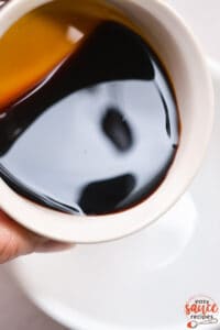 soy sauce being poured into a white mixing dish