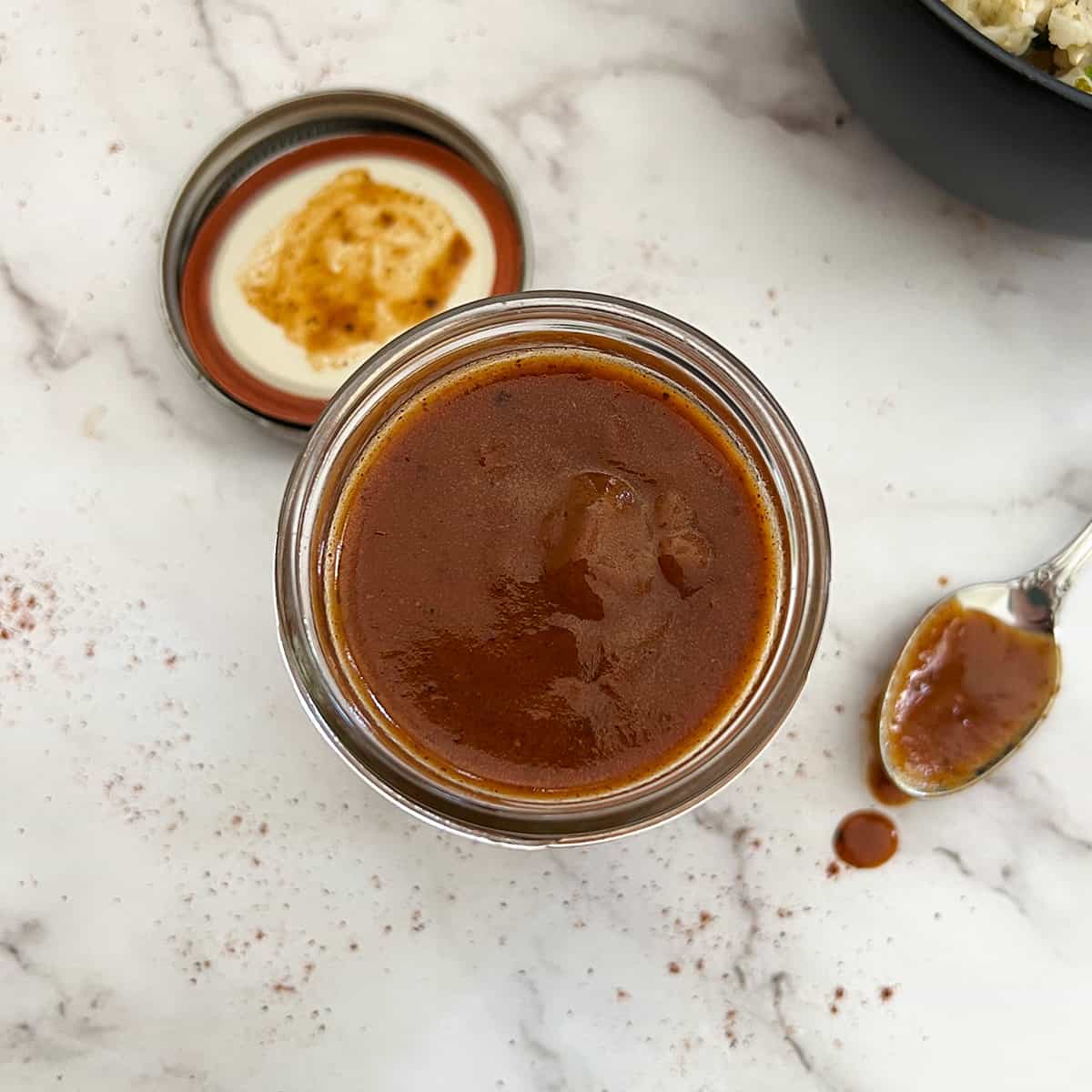 enchilada sauce in a clear jar with a spoon next to it