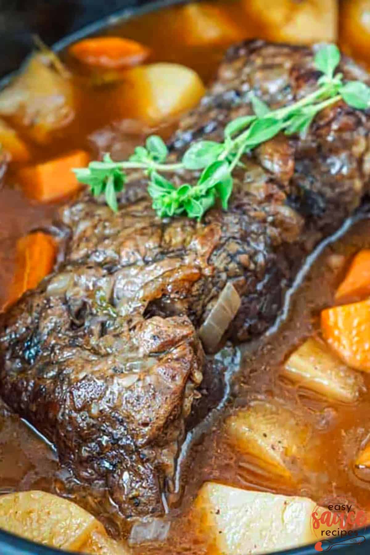 a pot roast in a slow cooker with carrots, potatoes, juices and herbs