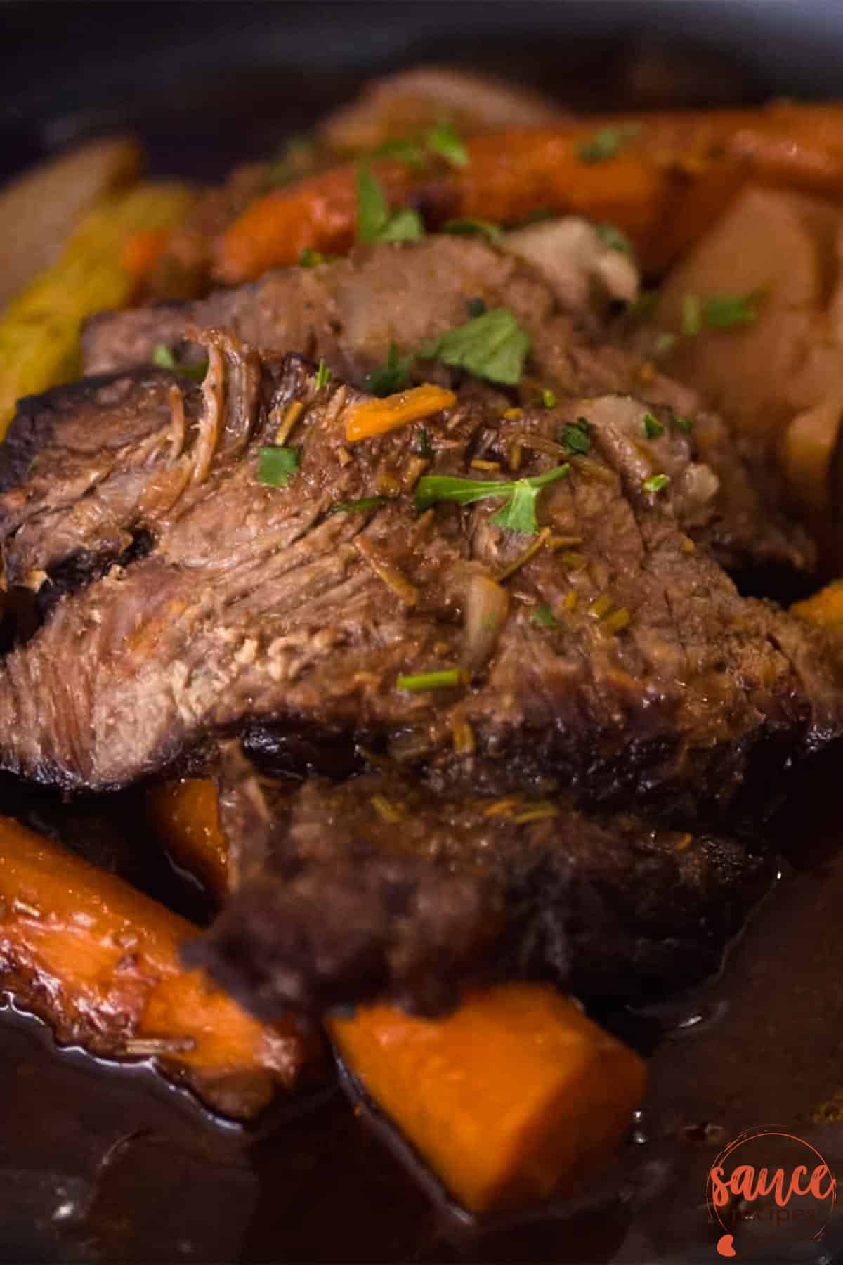 a pot roast cooking in a slow cooker with gravy and carrots