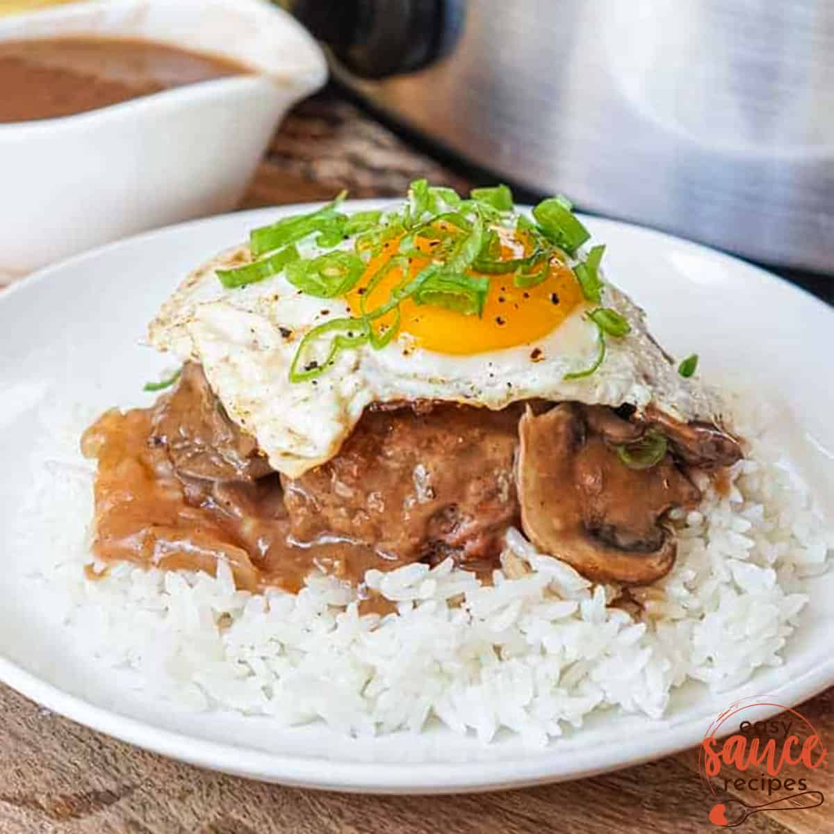 a plate with rice, pot roast, gravy, and a grilled egg with green onions