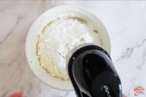 whisking powdered sugar into bowl