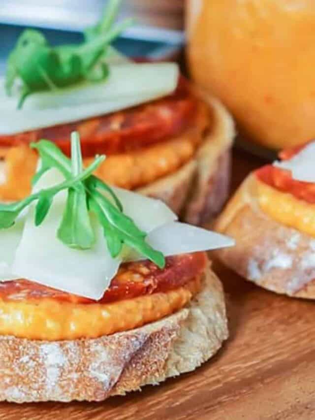 romesco sauce spread on baguettes with sliced chorizo and cheese