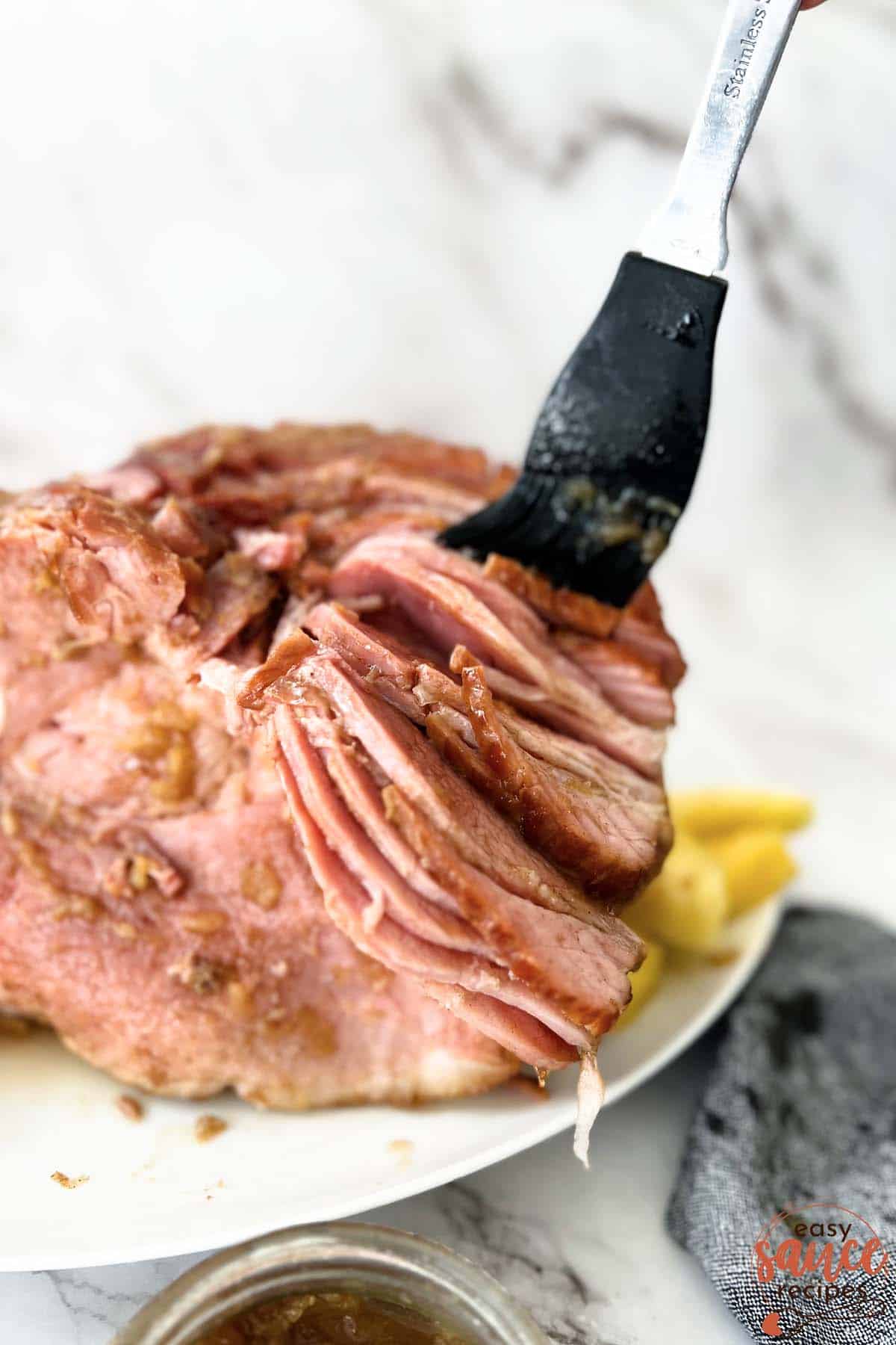 brushing a ham with pineapple glaze over the slices
