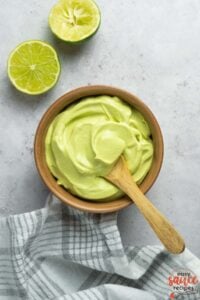 smoothly mixed avocado crema in a bowl with a wooden spoon