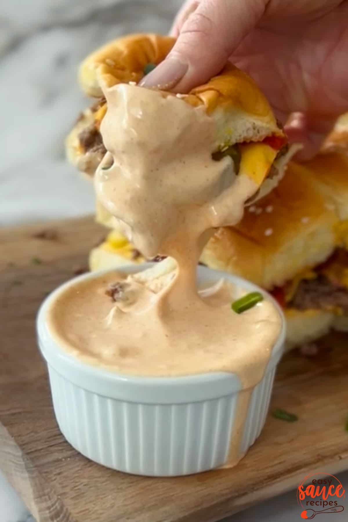 burger dipping into burger sauce in a white dish