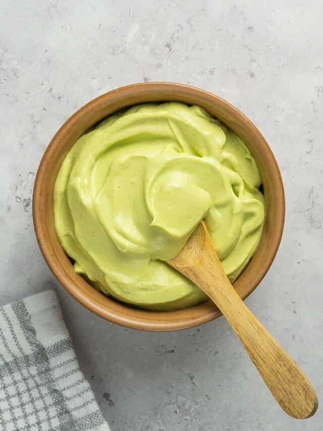 close up of avocado crema in a bowl with a wooden spoon