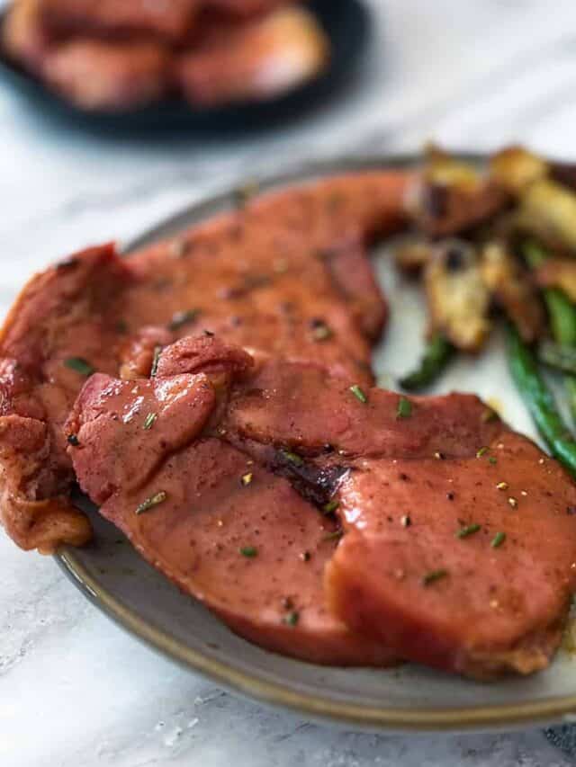 glazed ham steak on a plate with potatoes and green beans