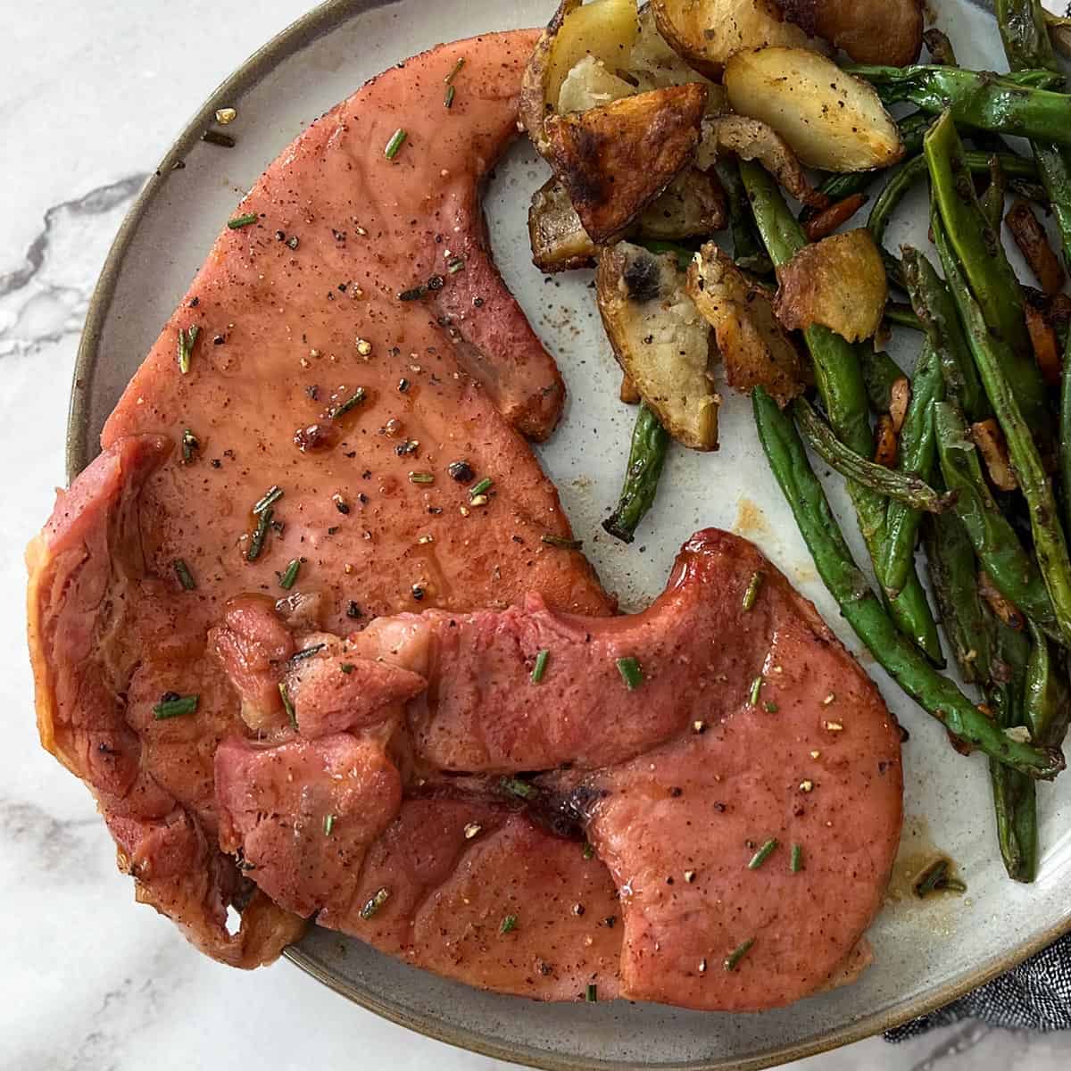 two glazed ham steaks on a dinner plate
