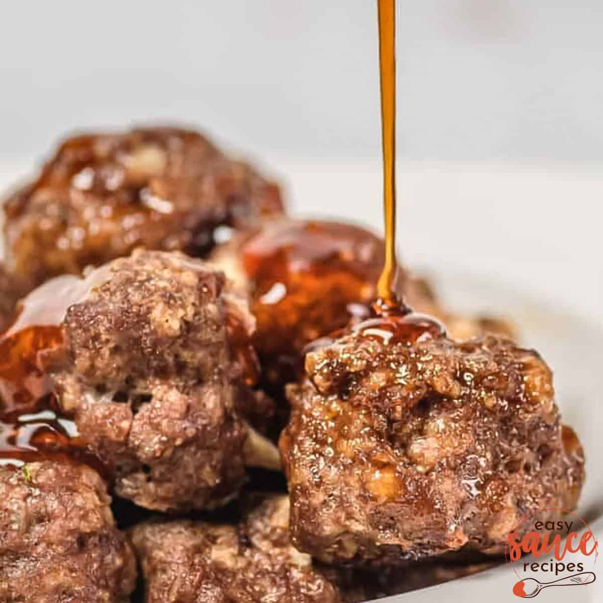 honey sriracha sauce being poured on a pile of meatballs