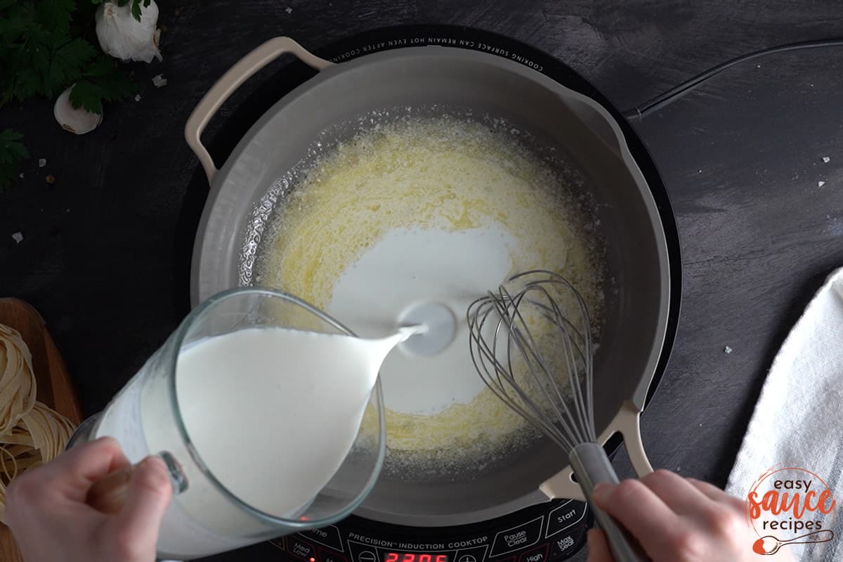 slowly whisking in heavy cream in a skillet