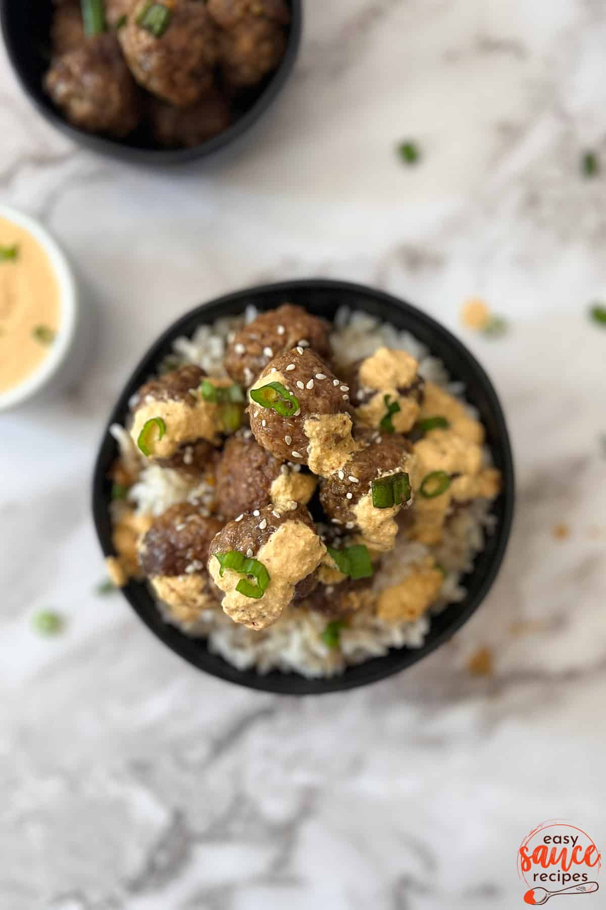 bulgogi sauce over meatballs and rice in a black bowl