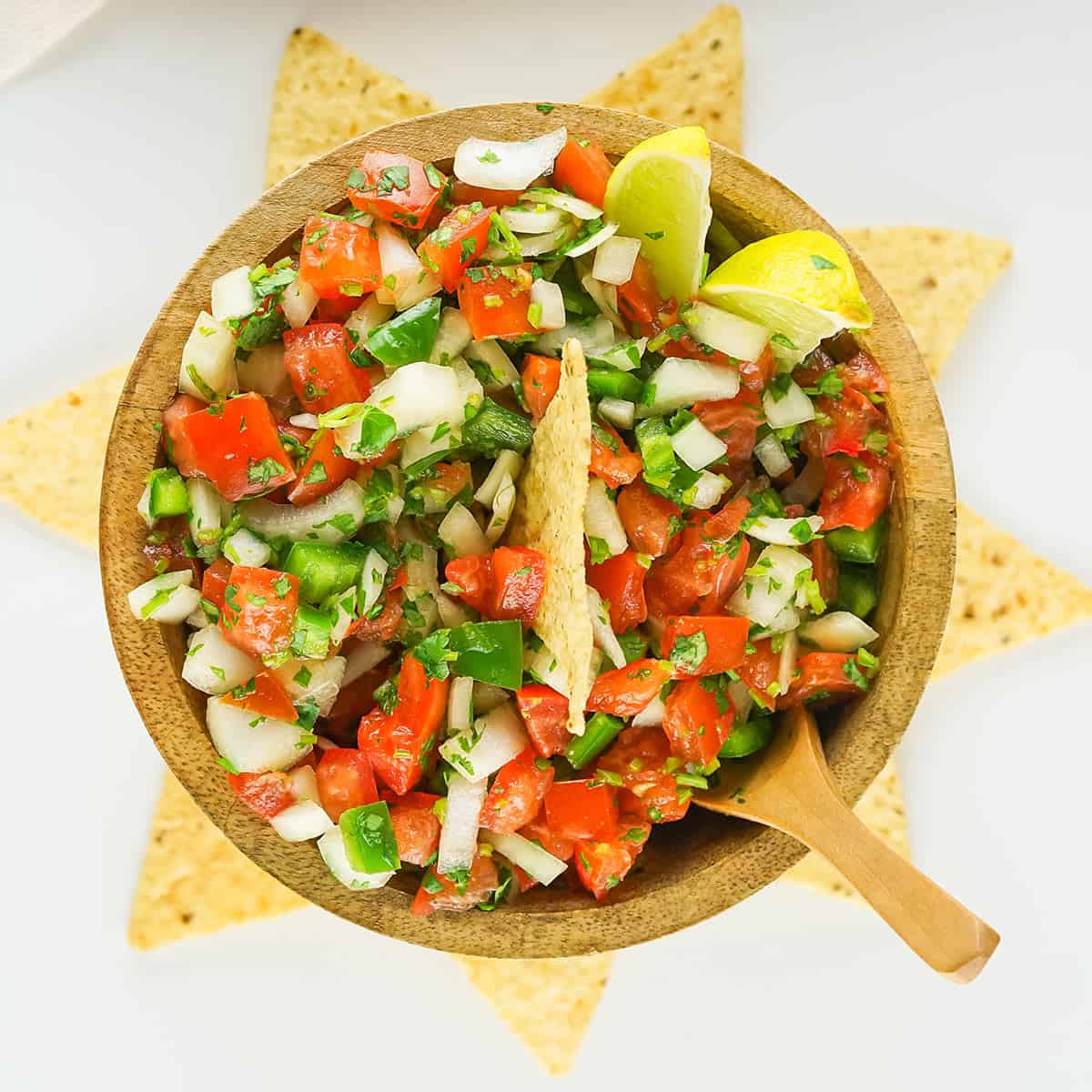 pico de gallo in a brown serving bowl with tortilla chips surrounding
