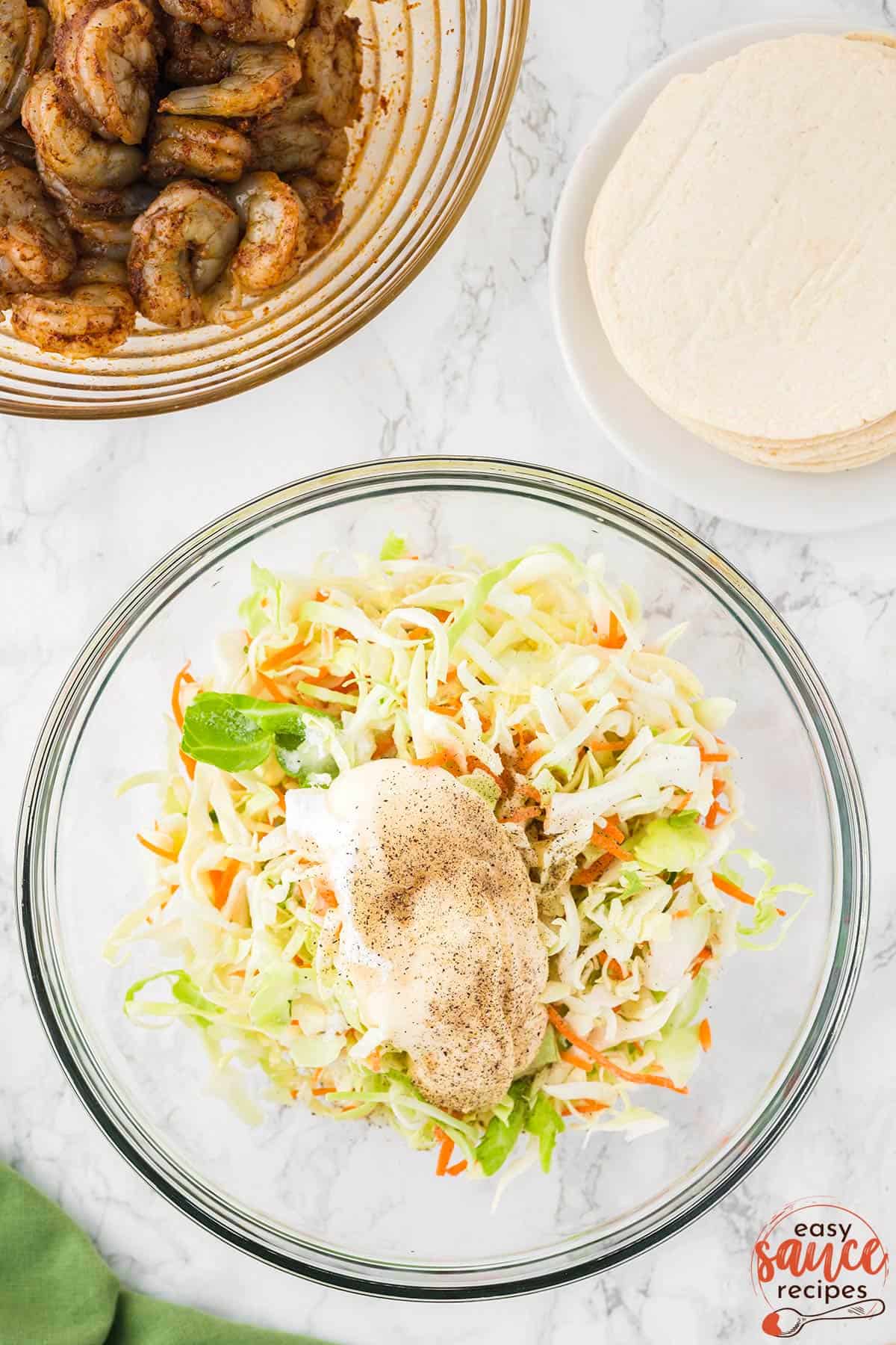 the dressing ingredients added on top of coleslaw mix in a bowl