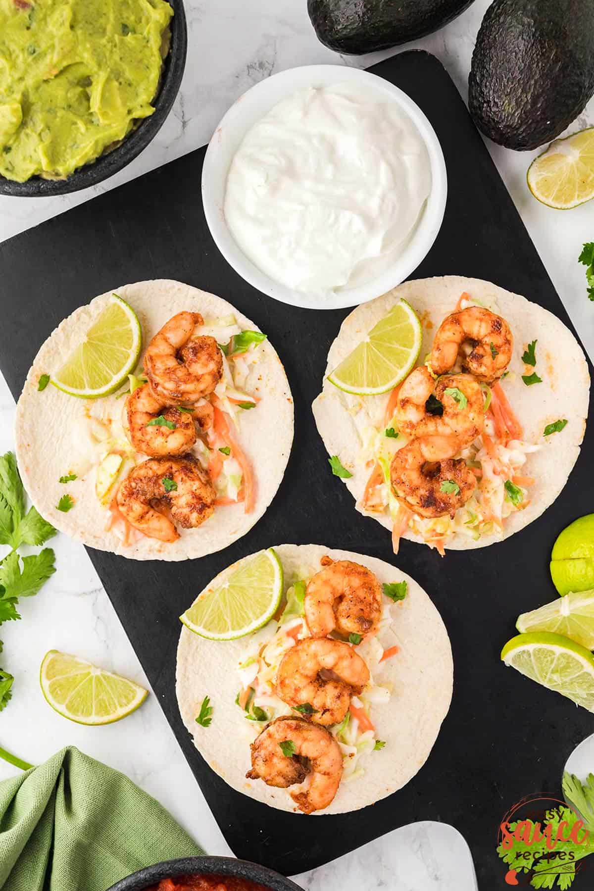 tacos with shrimp and fresh coleslaw on a plate with extra toppings of lime and avocado