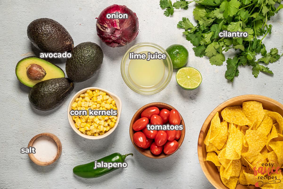 ingredients for avocado salsa with labels on a white surface in bowls