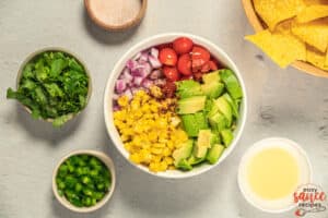 avocado salsa ingredients being added to a bowl