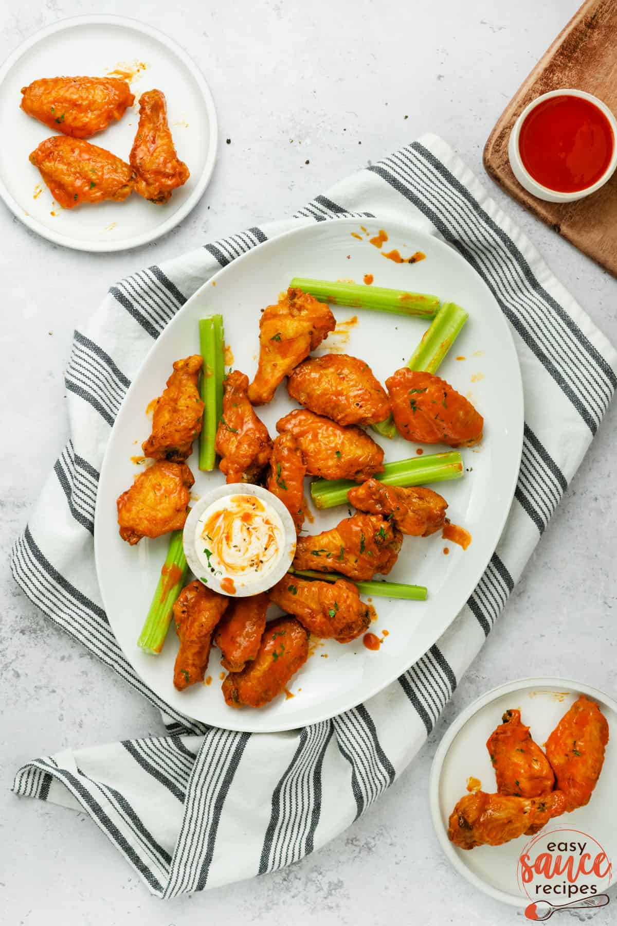 buffalo chicken wings on a white plate with buffalo sauce to the side