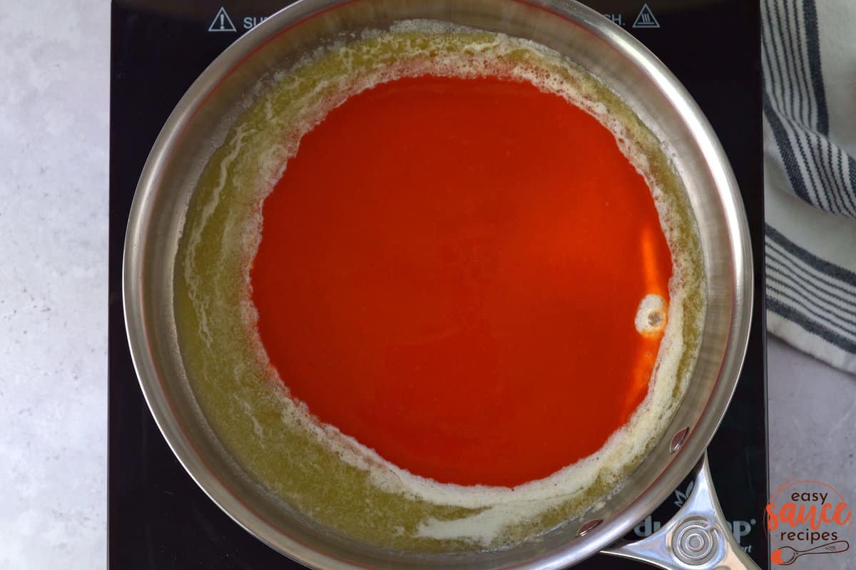 adding buffalo sauce and butter to a skillet