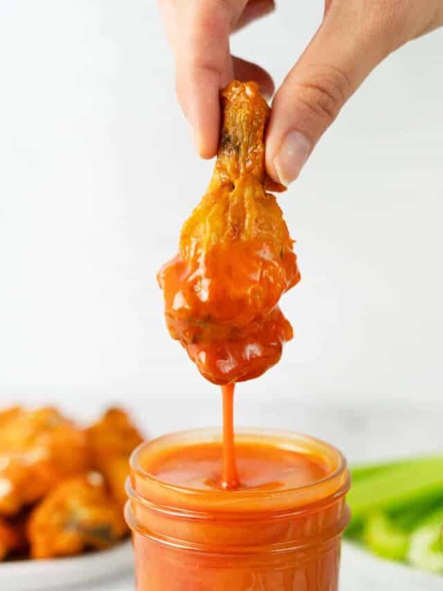 chicken wing dipping into buffalo sauce