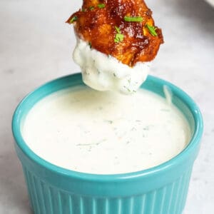a chicken wing being dipped in a dish of homemade ranch dressing