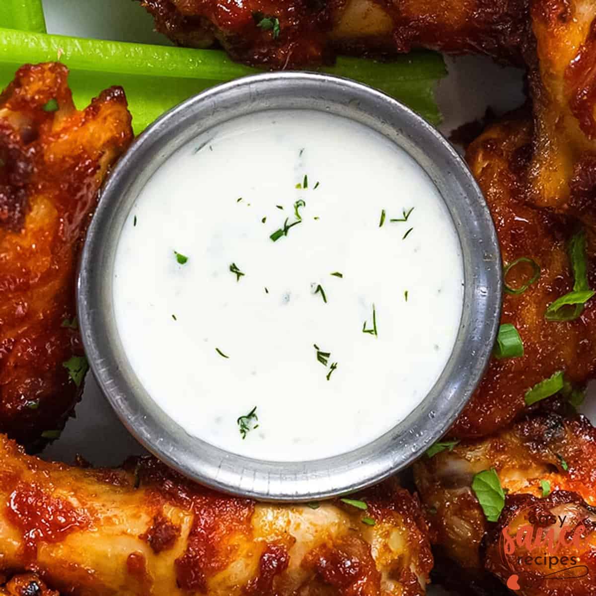 ranch dressing in a dipping bowl with wings around it