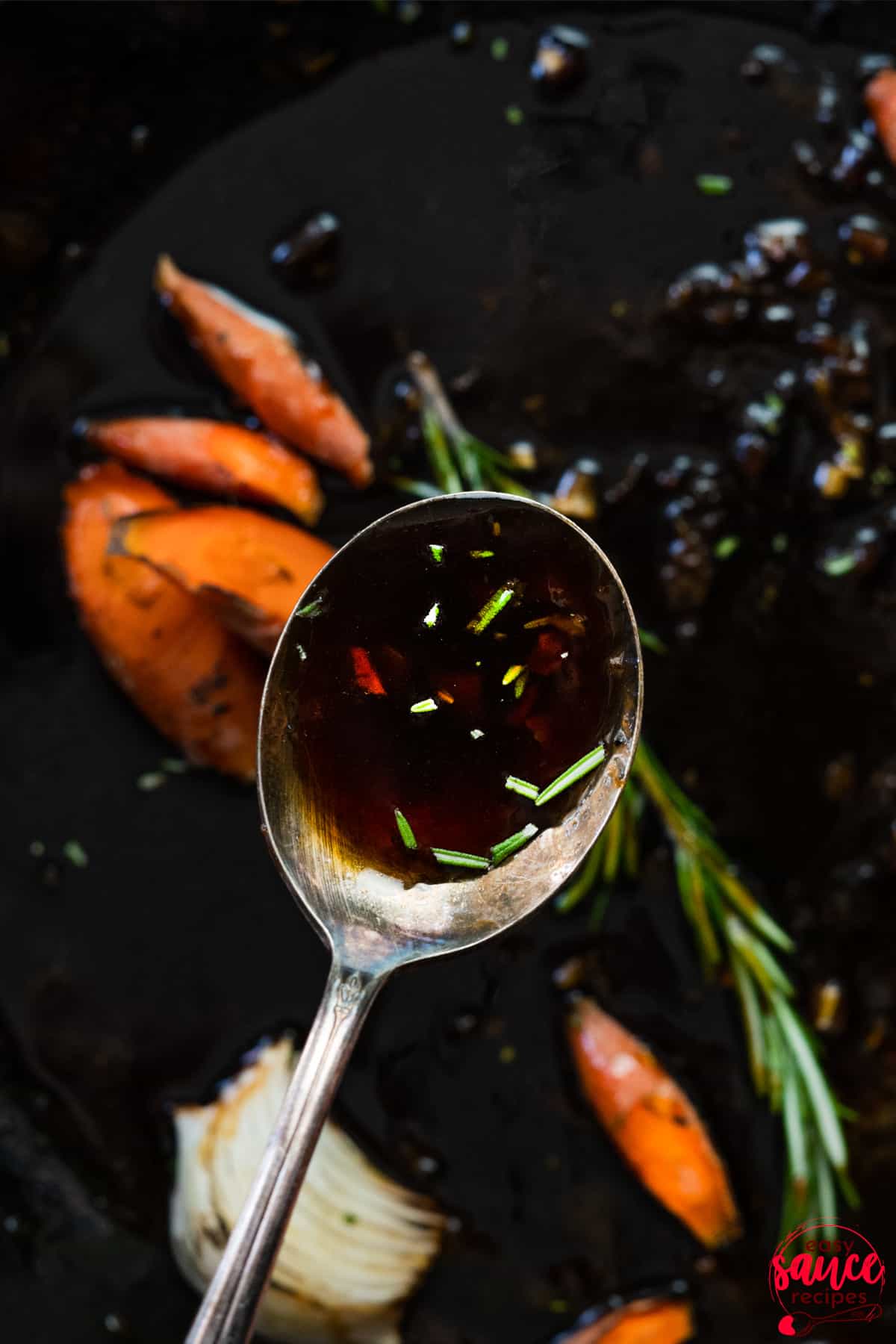 a spoon full of honey garlic sauce over a pan of carrots and onions