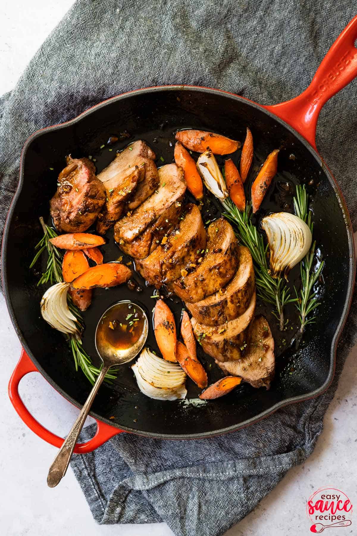 a skillet filled with onions, carrots, and pork tenderloin all glazed in honey garlic sauce