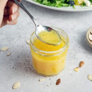 orange vinaigrette in a clear dish with a spoon