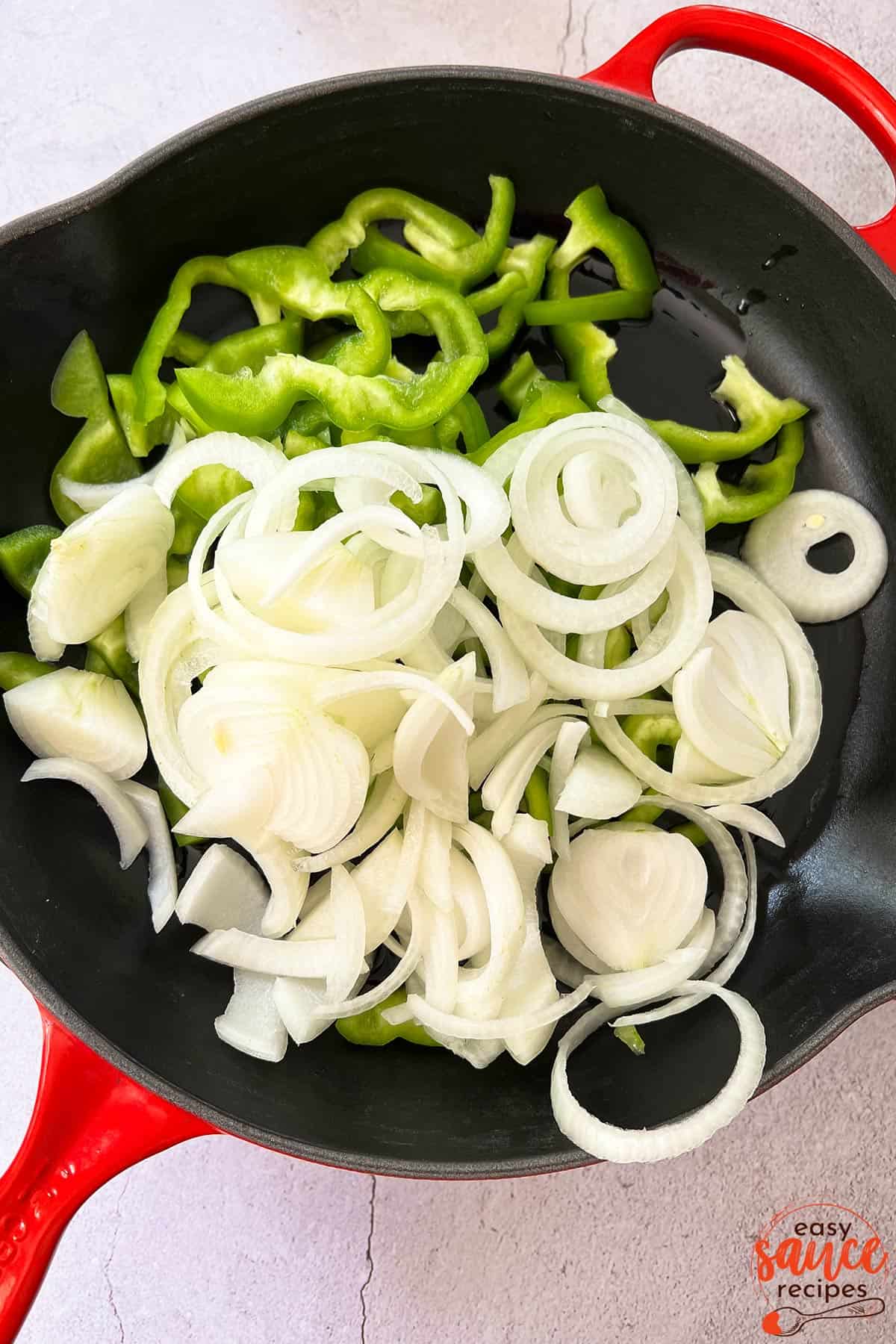 raw peppers and onions in a pan after being sliced