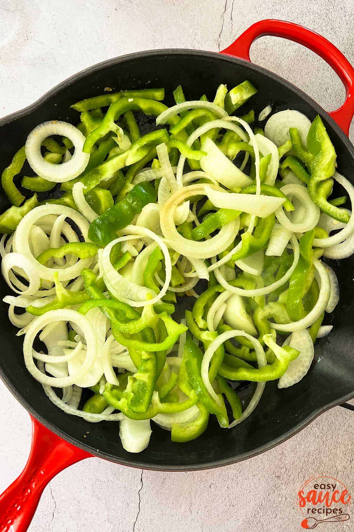 peppers and onions sliced and added to a pan with olive oil