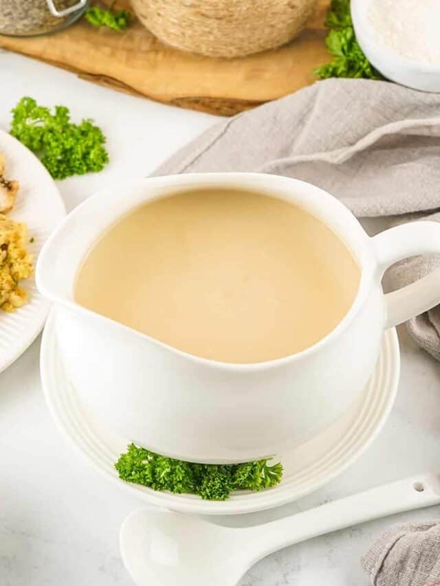 turkey gravy in a gravy boat on a plate with fresh parsley
