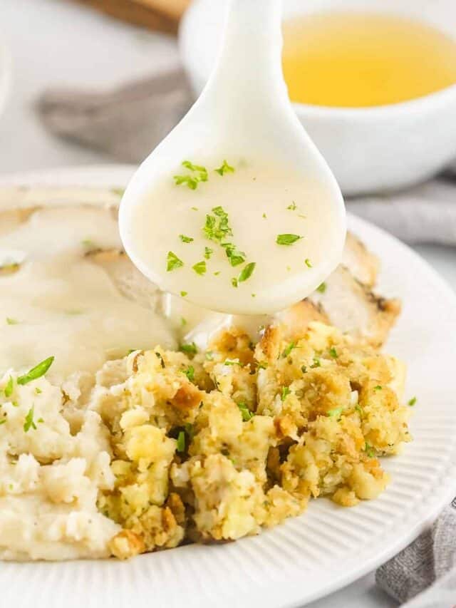 turkey gravy on a spoon pouring over stuffing