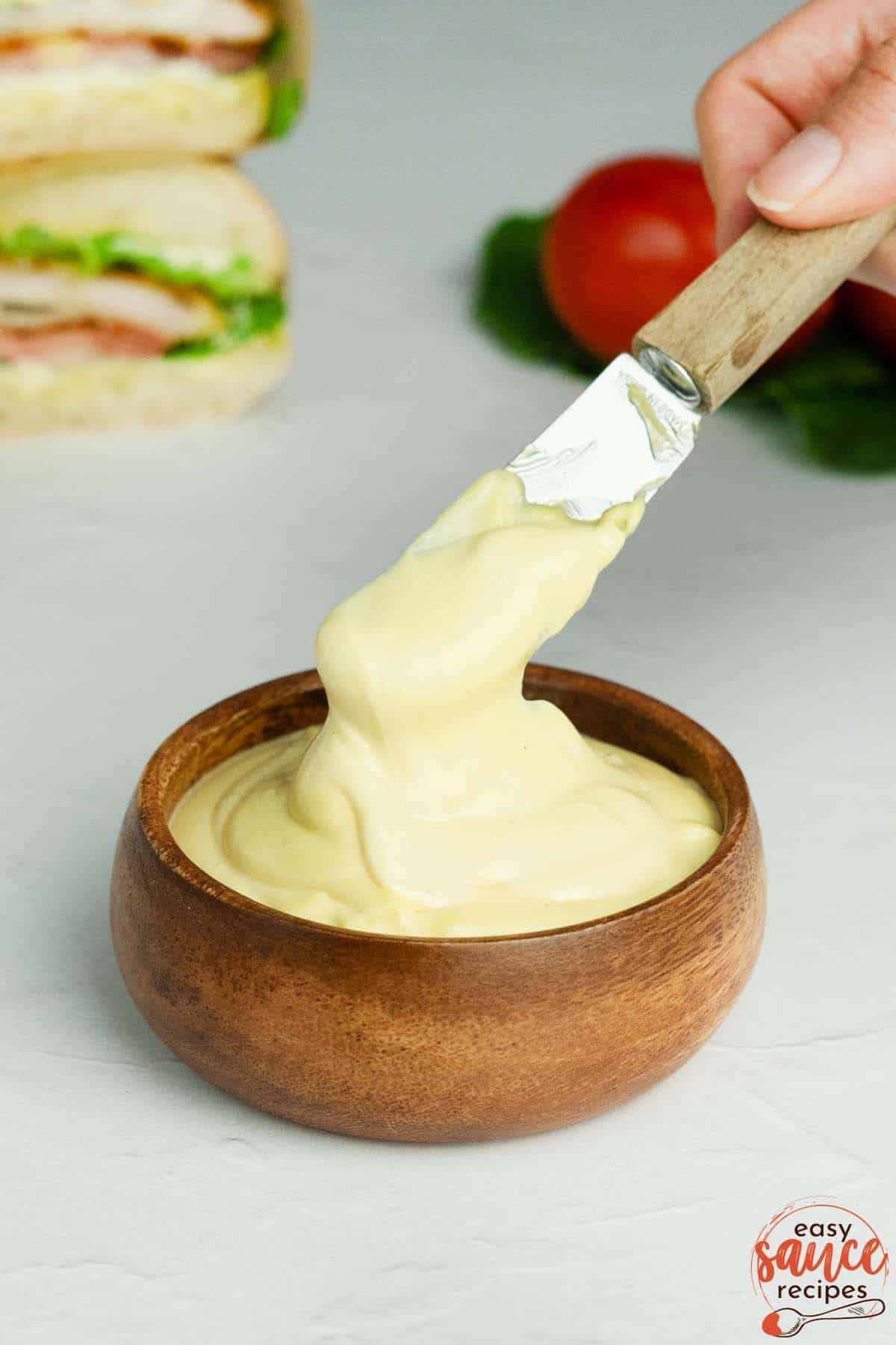 mayo mustard sauce in a small wooden bowl with a knife for spreading