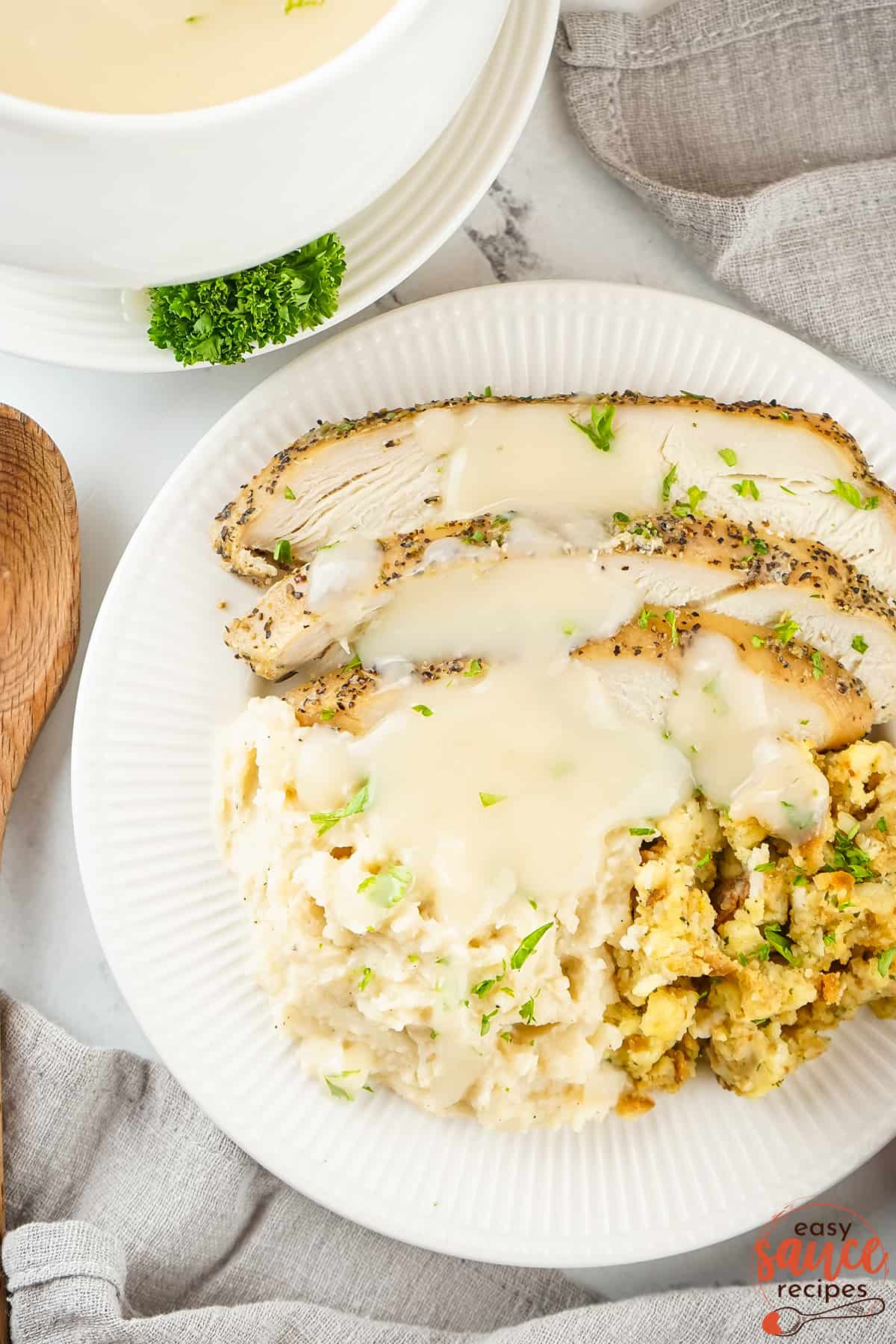turkey gravy poured over slices of turkey breast on a plate with stuffing and potatoes