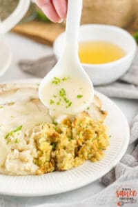 turkey gravy on a spoon pouring over stuffing