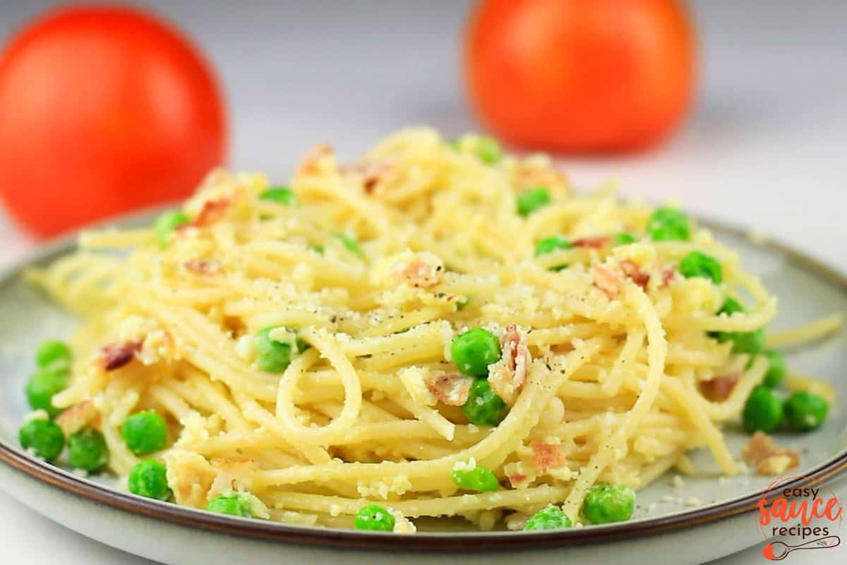 a completed plate of pasta carbonara with english peas
