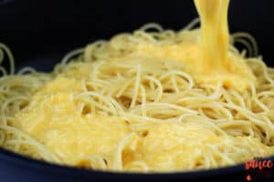 the egg and cheese mix being poured into the pot of warm pasta