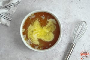 butter and honey added to a dish next to a whisk